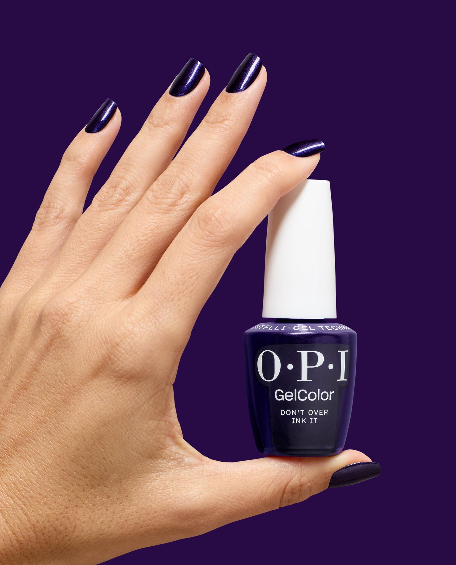 Hand with glossy dark purple shimmer nails holds OPI GelColor Don't Over Ink It gel nail polish bottle